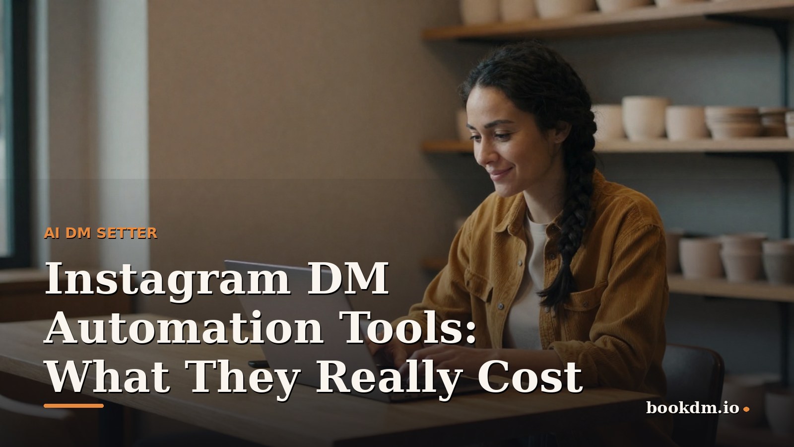 A woman around thirty with braided black hair in a mustard corduroy shirt, smiling as she compares prices on a laptop at a light wooden table in a warm ceramics workshop with shelves of pottery behind her, late morning light